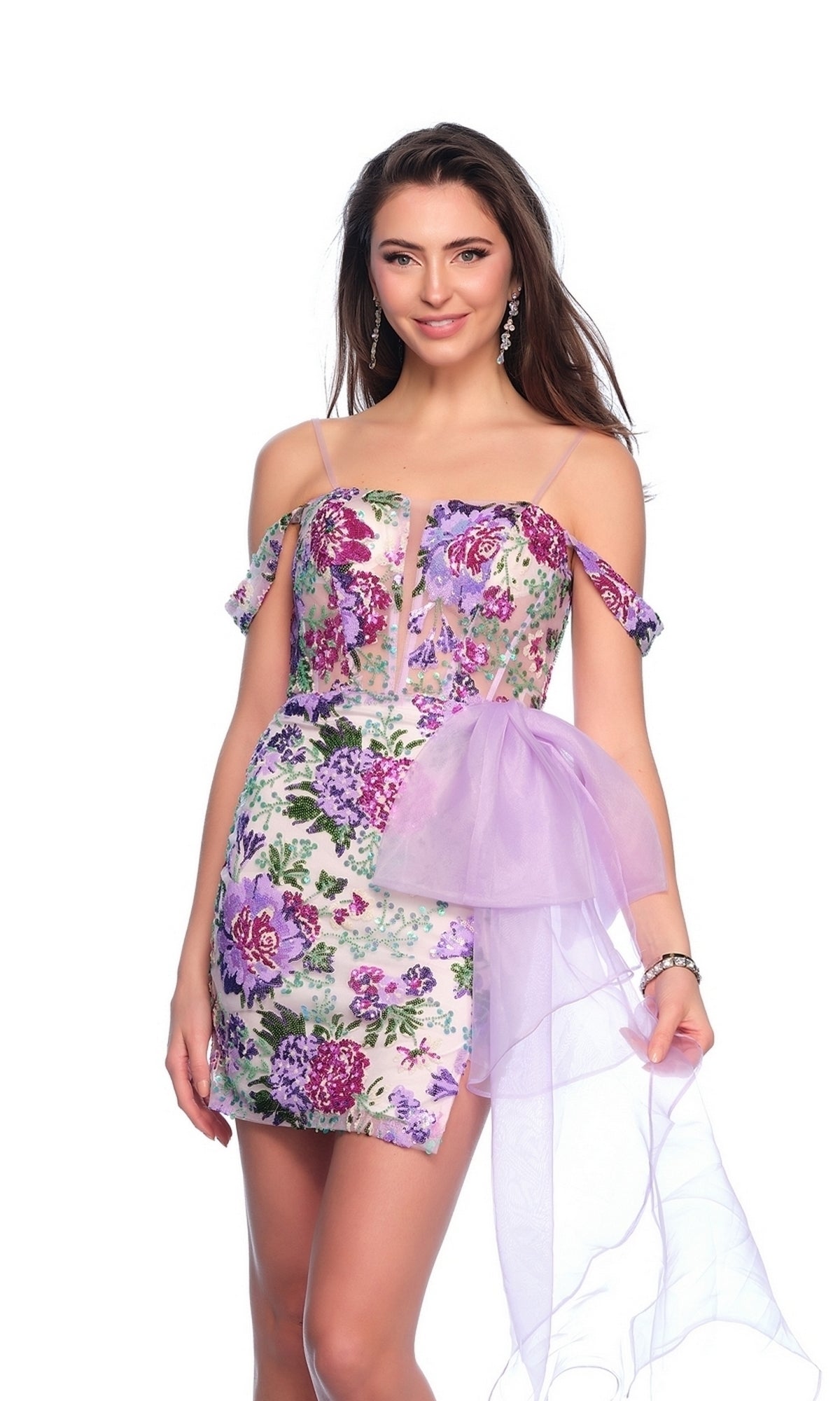 A woman stands against a white background wearing the Dave & Johnny Purple Print Hoco Dress 11770, featuring a short floral print design with a corset bodice and a sheer lilac sash.